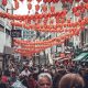 Vibrant red lanterns adorn a bustling street filled with crowds celebrating Chinese Lunar New Year in London.