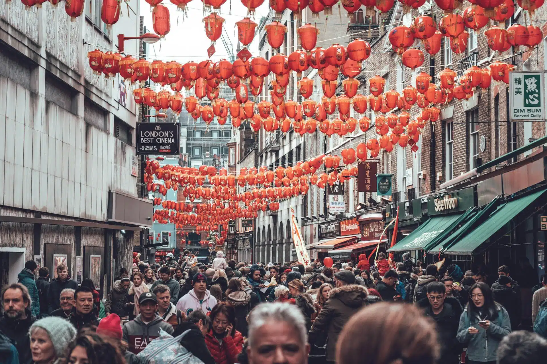 Vibrant red lanterns adorn a bustling street filled with crowds celebrating Chinese Lunar New Year in London.