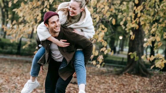 Couple enjoying a playful moment in a leafy park surrounded by autumn vibes, highlighting Romantic Things to Do in London for Free