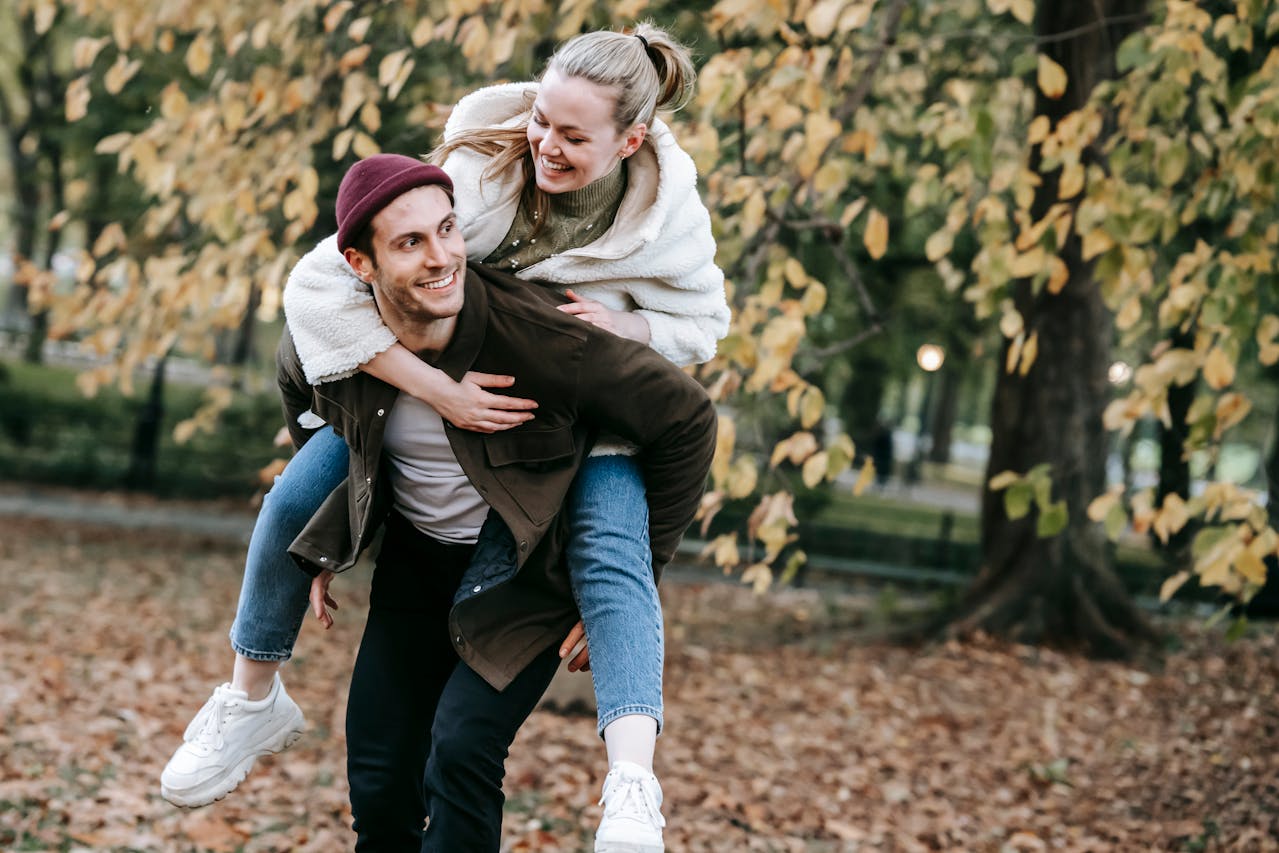 Couple enjoying a playful moment in a leafy park surrounded by autumn vibes, highlighting Romantic Things to Do in London for Free