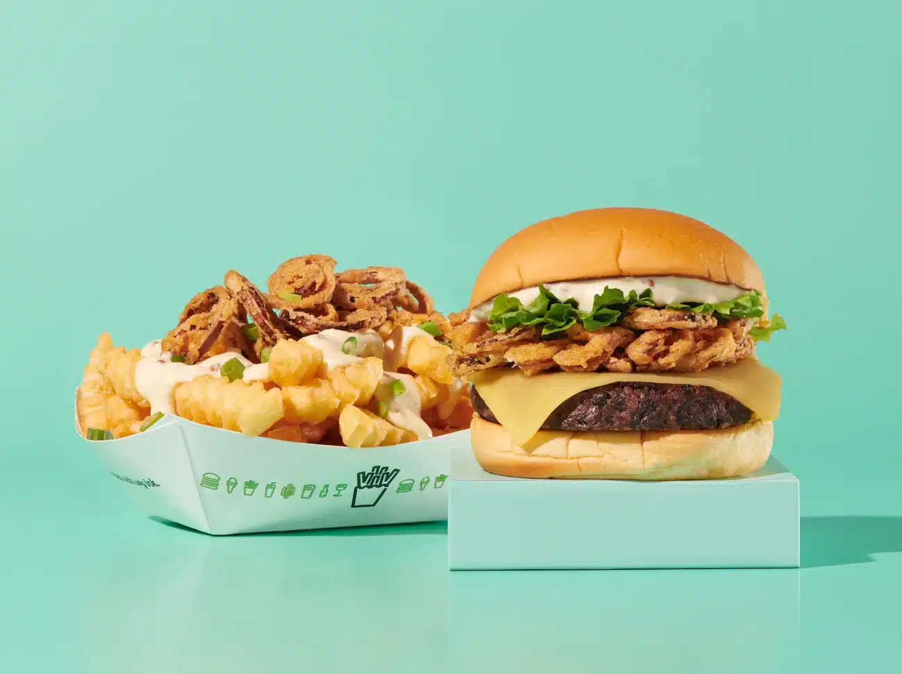 Shake Shack’s Plant-Powered Crispy Shallot Menu Is Back for Veganuary 2025 8 Crispy crinkle-cut fries topped with sauce and a gourmet cheeseburger from the new Shake Shack menu, perfect for food lovers.