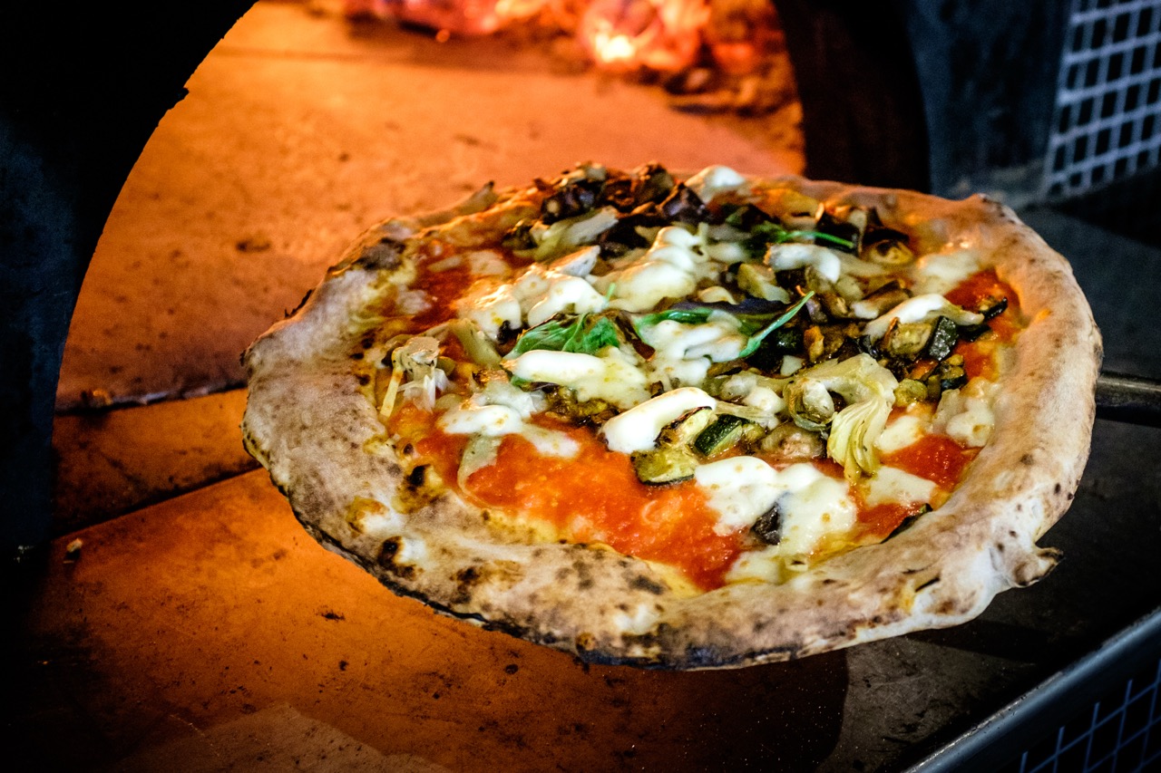 Wood-fired Santa Maria Pizza London, topped with fresh mozzarella, basil, and roasted vegetables, straight from the oven.