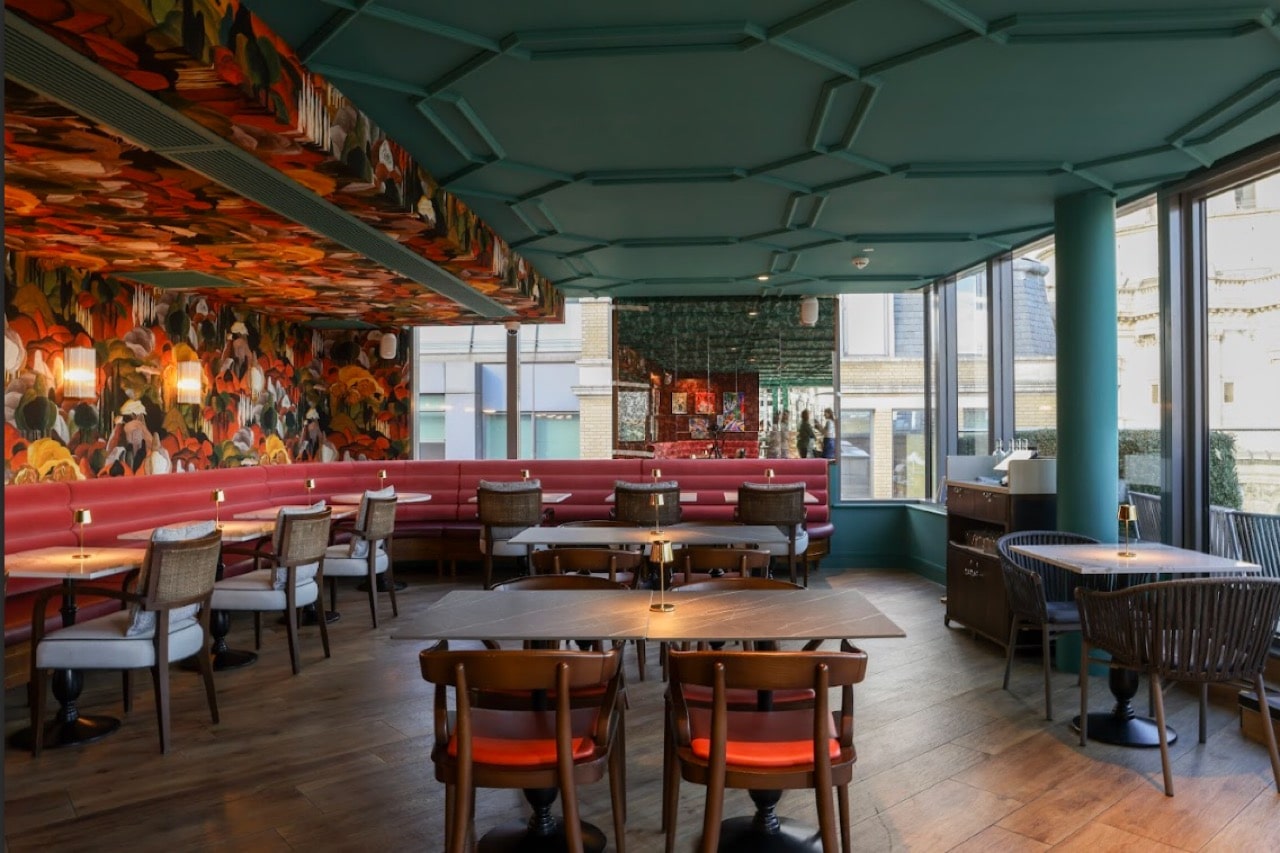 Chic interior of Sabine Rooftop Bar with vibrant floral decor, plush seating, and stunning city views, perfect for cocktails in London.